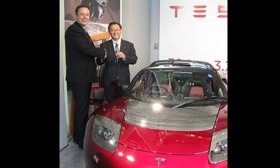 At a recent press event in Tokyo, Tesla's Elon Musk, left, presented Toyota president Akio Toyoda a metallic red roadster to commemorate their partnership. (Photo by Hans Greimel.)