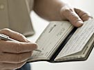 Image: A man holding a check book (© Image Source/Getty Images)